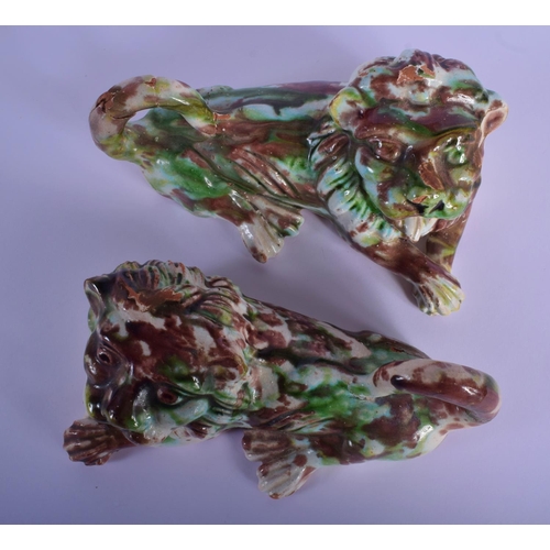 24 - A PAIR OF GREEN AND BROWN GLAZED POTTERY LIONS modelled scowling. 18 cm x 9 cm.
