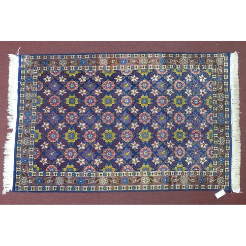 583 - A Persian Tehran rug, floral motifs on a blue ground, within floral border, 146 x 96cm