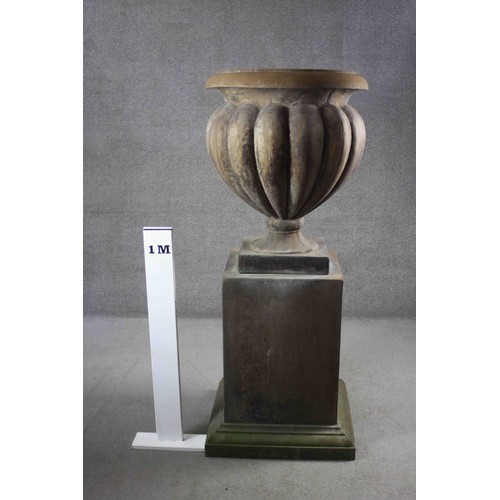 1 - A pair of very large aged stone effect fibreglass gadrooned design garden urns on square stepped pli... 
