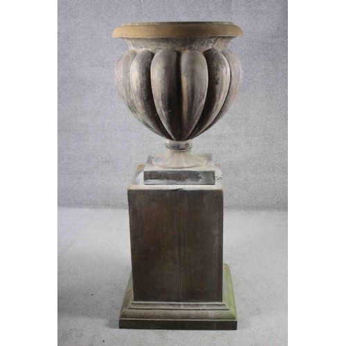 1 - A pair of very large aged stone effect fibreglass gadrooned design garden urns on square stepped pli... 