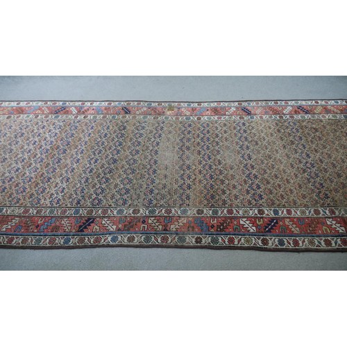 241 - A Caucasian runner with repeating stylised floral motifs across the biscuit ground within serrated p... 