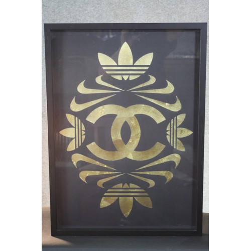 383 - A framed and glazed print on cloth, a composition from the Adidas, Nike and Chanel logos. H.73 W.53 ... 