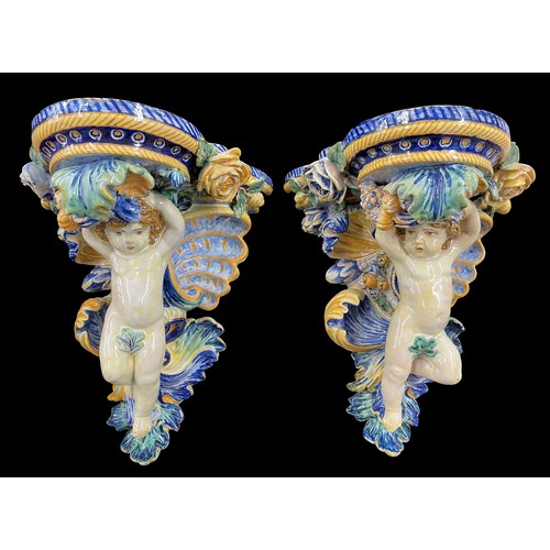 1 - Good large pair of majolica glazed pottery wall brackets, modelled as putti figural supports with sc... 