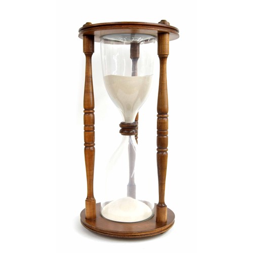 2023 - Hourglass sand timer, the twin flasks contained within an oak case united by three baluster turned c... 