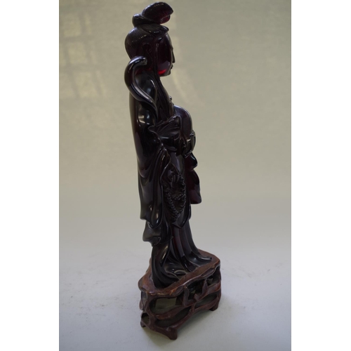 545 - A Chinese 'cherry amber' figure of Guanyin, on fitted hardwood stand, total height 24.5cm.... 