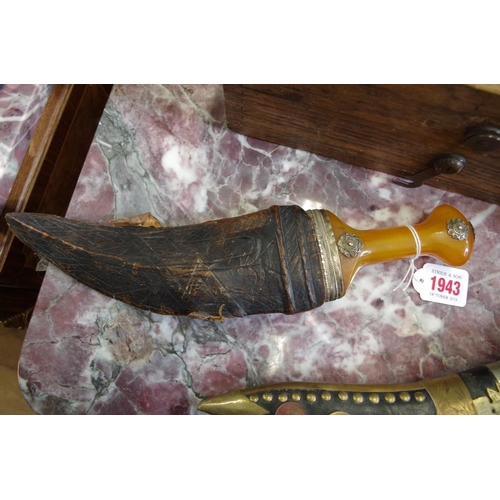 1943 - An Arab jambiya and leather sheath, with amber style handle. 