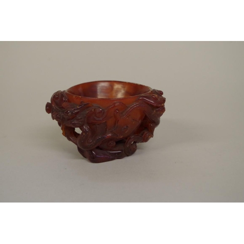 732 - A very rare Chinese carved amber libation cup, 17th century, carved in high relief with dragons and ... 