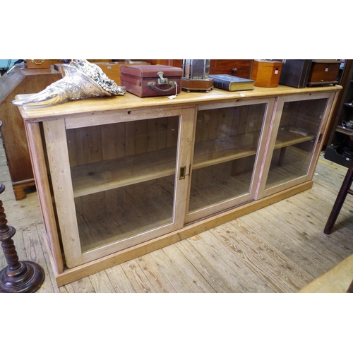1208 - A large antique pine cupboard, with three sliding glass panel doors, 248.5cm wide.