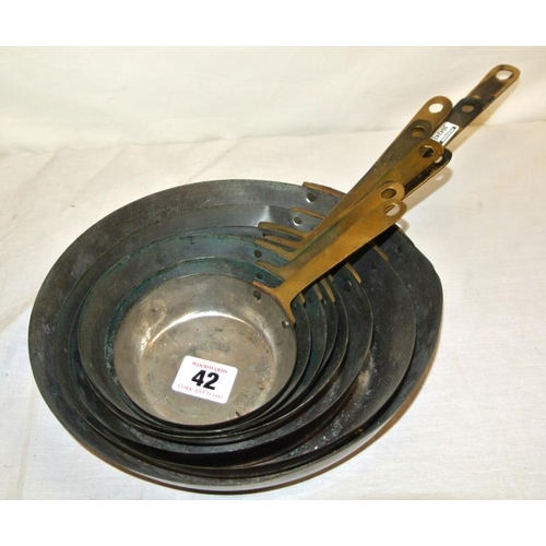 42 - Set of eight brass and copper saucepans with long handles
