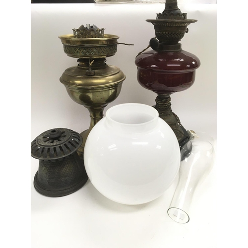 729 - Two oil lamps, one with a ruby glass reservoir.
