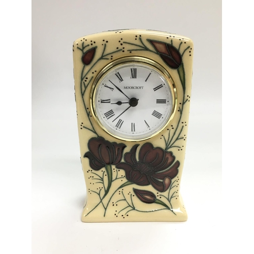 A Moorcroft clock with floral decoration on an ivory coloured ground ...