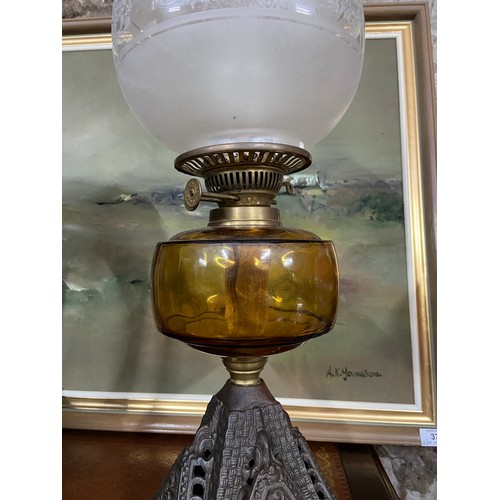 A 19th century cast metal, amber glass and frost glass shade paraffin lamp.
