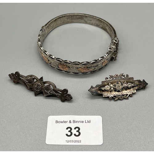 33 - Antique Silver bangle with yellow metal floral designs, Together with two silver brooches.