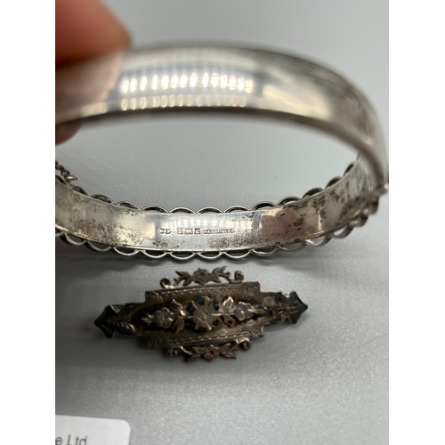 33 - Antique Silver bangle with yellow metal floral designs, Together with two silver brooches.