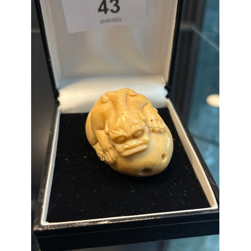 43 - A Japanese hand carved tagua nut netsuke in the form of a foo dog gripping onto a rock. [4cm in leng... 