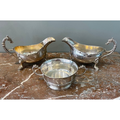 A three piece silver set of two sauceboats (x, y) and a loving cup (z). Sauceboats in 'Celtic' style with flying-scroll handle with dragon-head finial, ornate frieze rim with beaded sections separated by quatrefoils, raised on three pad feet cast with beast-heads. Loving cup with two handles with dragon-head finials, ornate frieze rim with beaded sections separated by quatrefoils, raised on moulded ring. All with hallmarks. By J B Chatterley & Sons Ltd, 1970s.