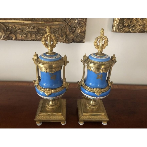 1064 - A pair of 19thC hand painted gilt mounted porcelain urns. 35cms h. Marked to the rear Brunfaut.