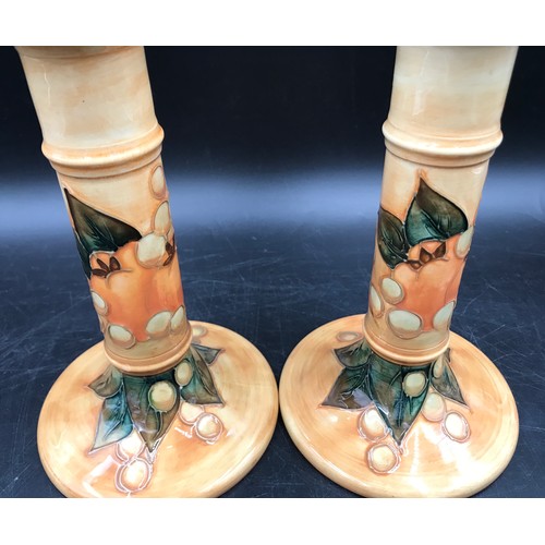 19 - A Moorcroft pair of candle sticks decorated with birds and fruit 20.5cms h and impressed base marks.