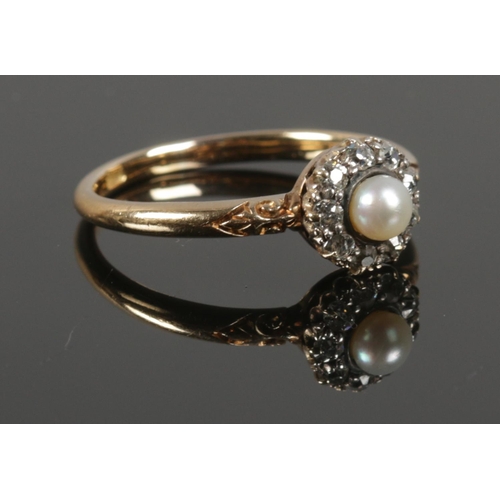 An 18ct Gold ring, set with central pearl surrounded by 9 small diamonds (1/32ct) on scrolled bridge. Total weight: 3.84g