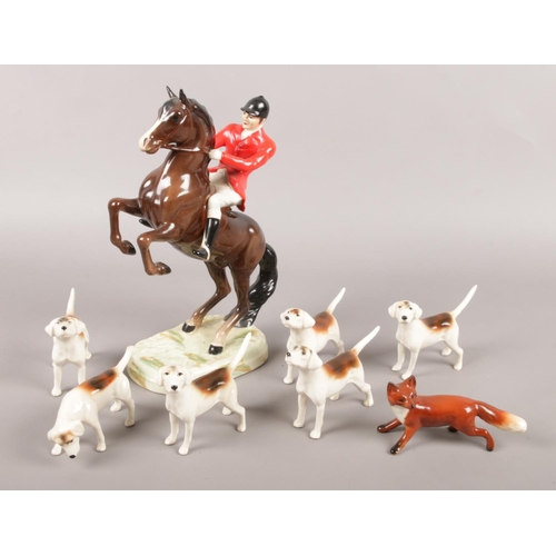 A collection of Beswick fox hunt figures. Includes rider on rearing horse, six fox hounds and a fox.
