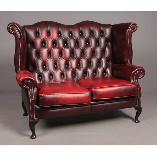 An ox blood deep buttoned studded leather Chesterfield two seat sofa.