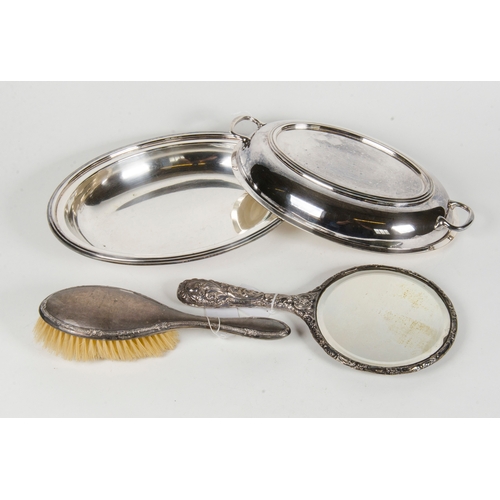16 - A silver embossed dressing table mirror, along with one other brush, an entree dish and cover.