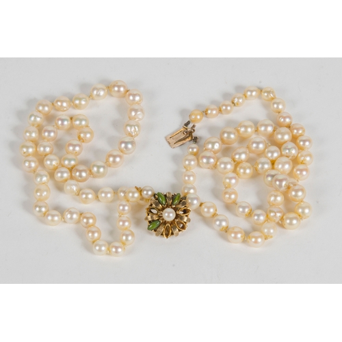 99 - A Two Strand Cultured Pearl Necklace, with a 9 carat clasp, set with green stones.