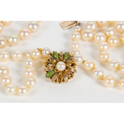 99 - A Two Strand Cultured Pearl Necklace, with a 9 carat clasp, set with green stones.