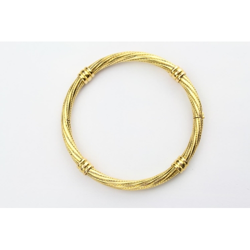137 - A Gilded bangle of a swirl design with safety catch.