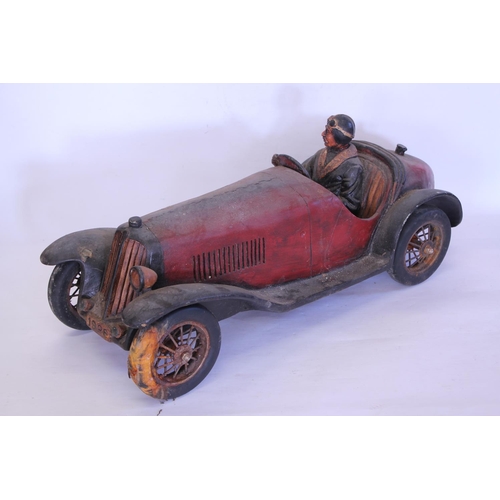 666 - A Resin model of a Racing Driver in a Race Car. Measuring: 60cms long. (AF).