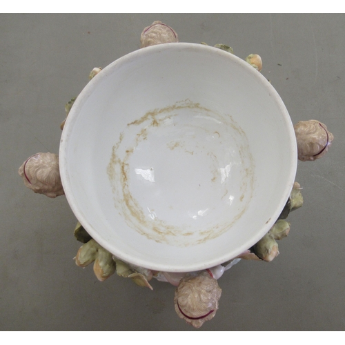 25 - An early 20thC Bavarian floral encrusted porcelain centrepiece bowl, supported by standing cherubs, ... 