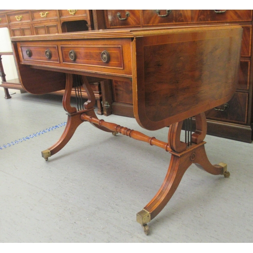 32 - A modern reproduction of a 19thC yewwood finished sofa table with two inline drawers and two facsimi... 