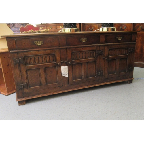 35 - A Titchmarsh & Goodwin Old English style carved and panelled oak sideboard, comprising three inl... 