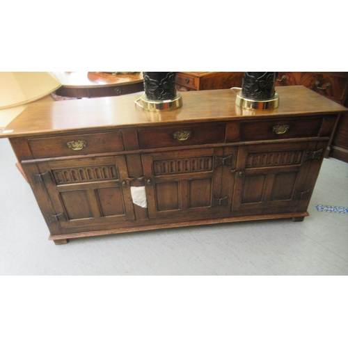 35 - A Titchmarsh & Goodwin Old English style carved and panelled oak sideboard, comprising three inl... 
