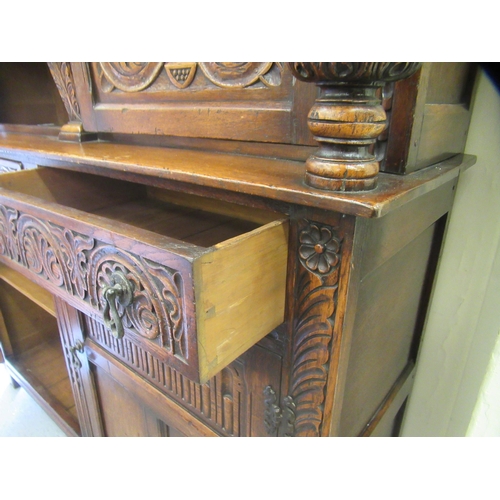 50 - A 1920s/30s carved oak court cupboard, the frieze drawer over a pair of recessed doors and outset fl... 