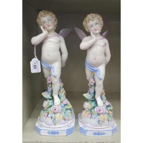 60 - A pair of 20thC Continental standing porcelain figures, each Cupid with a bow and a quiver of arrows... 