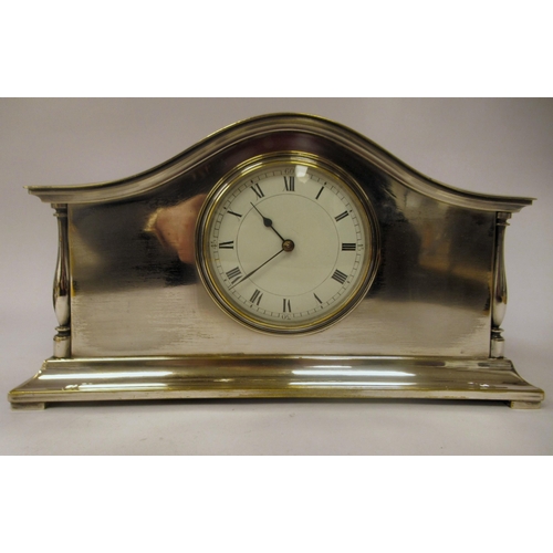 50 - A 1930s elecroplated brass mantel timepiece with a low arched case and spindled baluster flank pilla... 