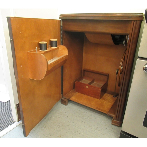 25 - An Art Deco mahogany finished sewing cabinet, containing a Singer manual sewing machine, model V1455... 