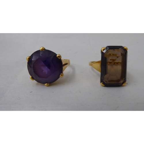 46 - Two Bahrainian yellow metal rings, one set with a smokey quartz, the other an amethyst coloured ston... 