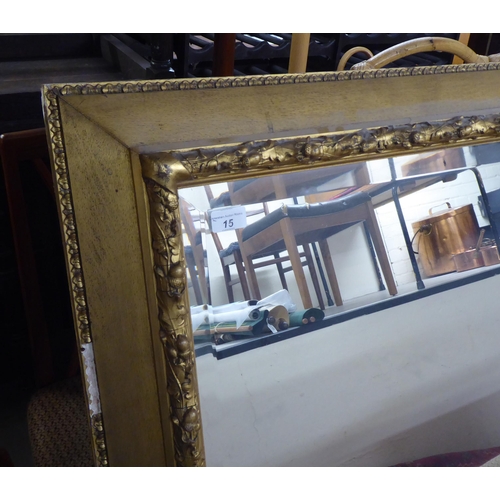 15 - An early/mid 20thC mirror, the bevelled plate set in a foliate moulded gilt frame  35