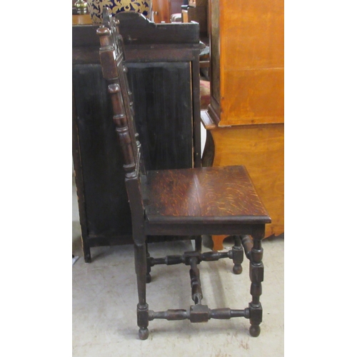 25 - A late 19thC carved and stained oak hall chair, the solid seat raised on turned and block forelegs
