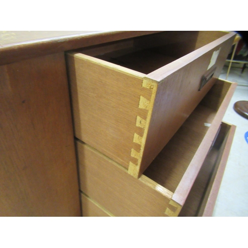 35 - A 1970s teak sideboard with a sliding door, a central bank of three drawers and two open shelves, ra... 