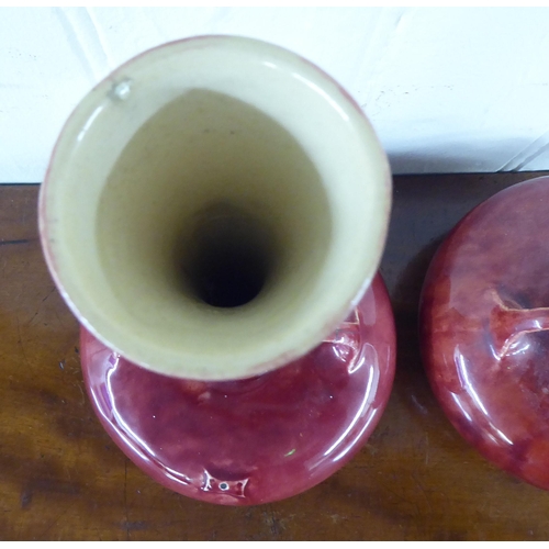 36 - A pair of streaky red glazed pottery vases, each with a tall, slender neck, twin handles and a bulbo... 