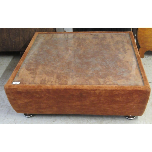 44 - A fabric covered coffee table with a glass top  12