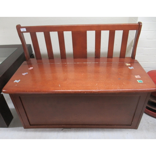 49 - A child's modern mahogany finished bedroom bench with a lath back, over a hinged seat, on a plinth  ... 