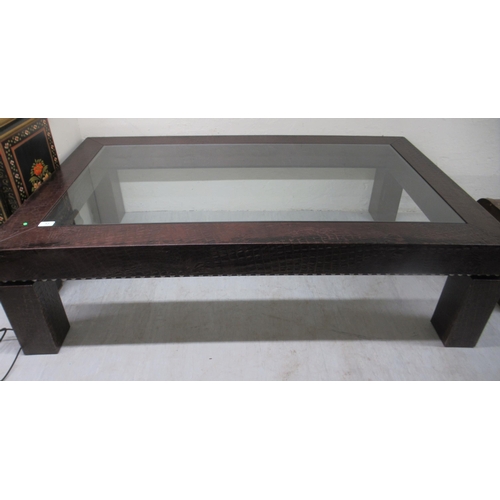 53 - A modern coffee table with an inset glass top, in a faux crocodile skin effect hide frame, raised on... 