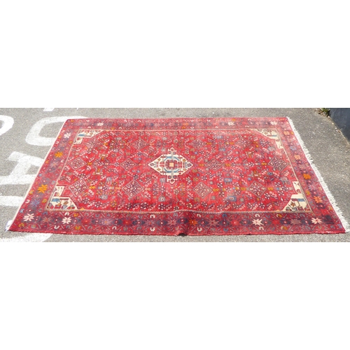 6 - A Persian rug, decorated with stylised designs on a red ground  60