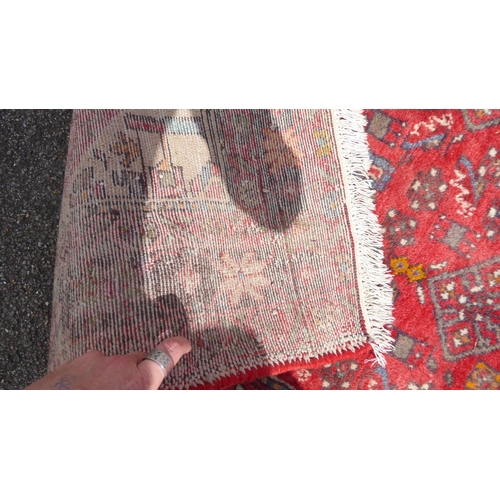 6 - A Persian rug, decorated with stylised designs on a red ground  60