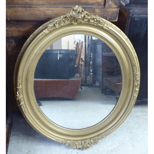 7 - A 20thC mirror, the oval plate set in a Victorian style moulded gilt frame  39