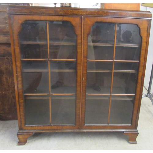 8 - An Art Deco walnut display cabinet with a pair of glazed doors, raised on bracket feet  47